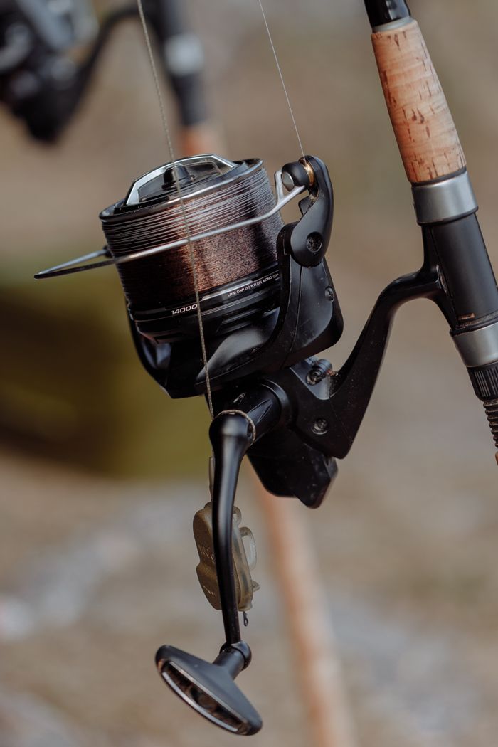 Detailed view of a fishing reel attached to a rod, perfect for angling enthusiasts.